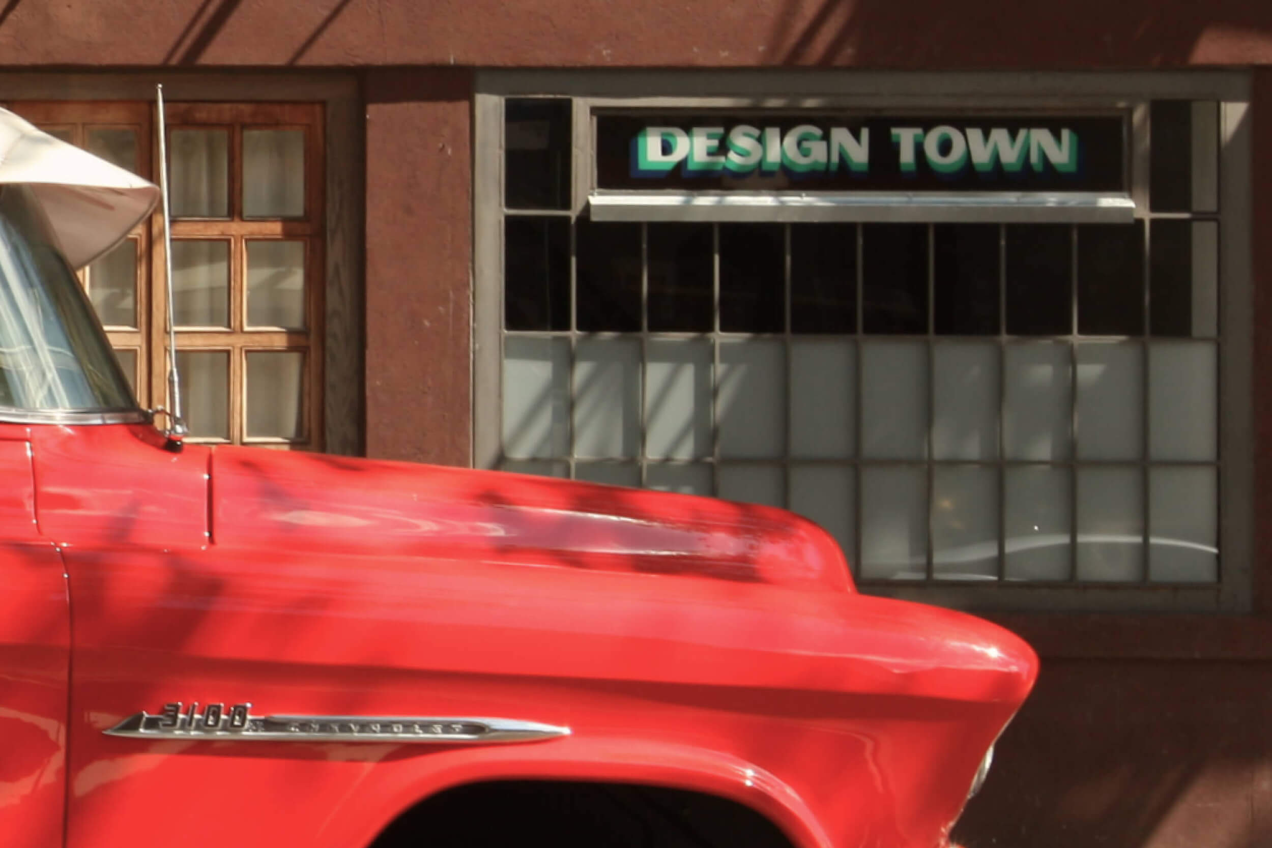 The storefront of Design Town with an old red pickup truck in the foreground